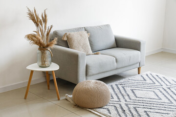 Grey sofa with cushion and pampas grass on coffee table in light living room