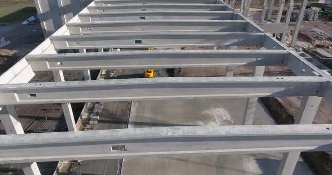 Drone video of a construction site of an industrial building with columns and beams and a heavy-duty crane