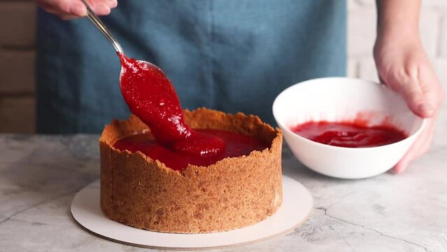 Woman Female hands making cheesecake, spoons out strawberry confiture in the kitchen video slow motion footage