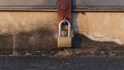 A close up of old padlock with an rusty iron latch on a cement chest