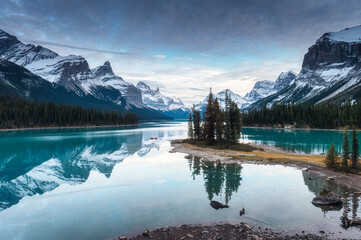 View of Spirit Island with Canadian Rockies and tourist rowing canoe in Maligne Lake at Jasper...