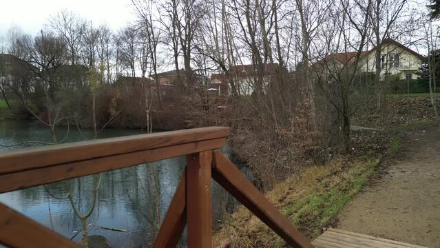 pedestrian bridge over a small gorge and a stream. it consists of two steel crossbeams. as the surface and railing of the bridge is made of brown painted planks. is long and narrow. in the wild