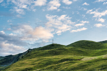 Wooden cross on top of mountain and bright sky in Swiss Alps at Switzerland