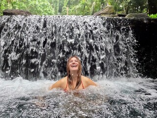 Young girl taking a bath in a waterfalls in Philippines. High quality photo