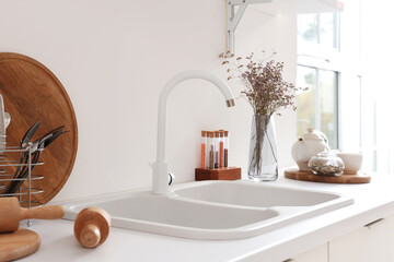 White counter with sink, condiments and dried flowers in interior of modern kitchen