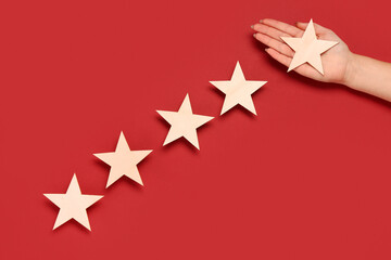 Female hand with five stars rating on red background. Customer experience concept