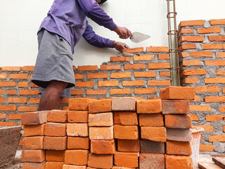 A builder is working on arranging bricks with cement to make a wall