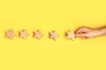 Female hand with five stars rating on yellow background. Customer experience concept