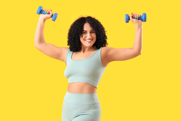 Sporty adult woman with dumbbells on yellow background - obrazy, fototapety, plakaty