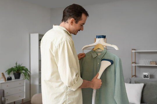 Young man steaming shirt at home