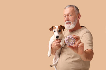 Middle-aged man with cute dog and toy on beige background