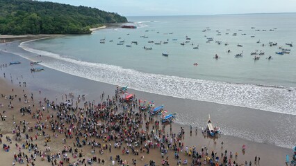 Pangandaran Beach, West Java, Indonesia. A stunning scene where a group of tourists celebrate the beauty of nature while enjoying the hajat laut, an interesting cultural procession.