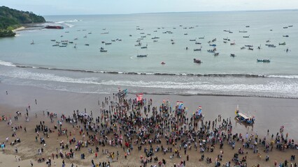 Pangandaran Beach, West Java, Indonesia. A stunning scene where a group of tourists celebrate the beauty of nature while enjoying the hajat laut, an interesting cultural procession.