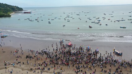 Pangandaran Beach, West Java, Indonesia. A stunning scene where a group of tourists celebrate the beauty of nature while enjoying the hajat laut, an interesting cultural procession.