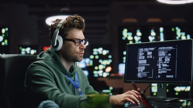 IT programer listening headphones working desktop computer data center closeup