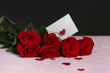 Red roses and envelope on pink background