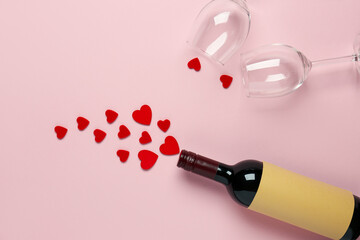 Bottle of wine, glasses and hearts on pink background. Valentine's Day celebration