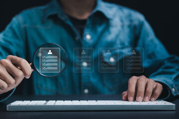 Businessman use magnifying glass to focus on online employee evaluation form. Human resource management (HR), Check resume, Screening employee information and job applicants.