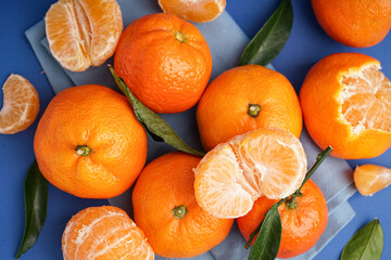Tasty tangerines with napkin on blue background