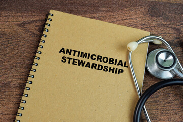 Concept of Antimicrobial Stewardship write on book with stethoscope isolated on Wooden Table.