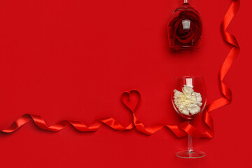 Glasses with beautiful flowers and ribbon on red background. Valentine's Day celebration