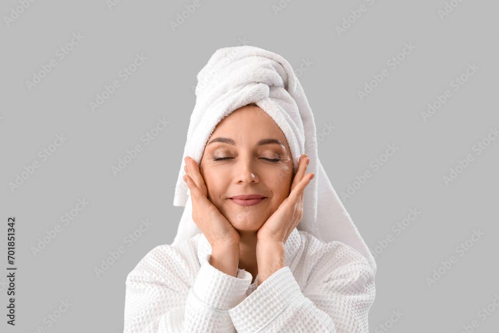 Wall mural Mature woman in bathrobe after shower on light background, closeup