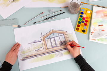 Architect illustrator working on hand drawn illustration of a modular prefabricated house  using watercolor paints and brush. - obrazy, fototapety, plakaty