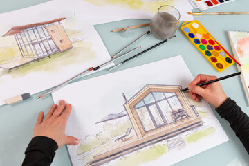 Architect illustrator working on hand drawn illustration of a modular house  using black pencil to draw lines on a sketch. - 701852137