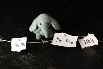 Paper pieces with barbed wire and toy elephant on dark background. Domestic violence concept