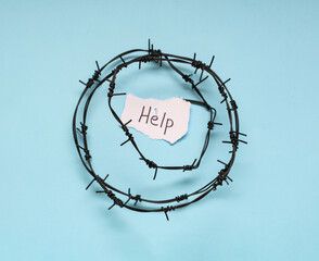 Paper piece with word HELP and barbed wire on blue background. Domestic violence concept