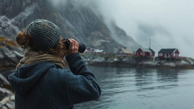 Seaside Town overlooking a foggy fjord, a small Scandinavian fishing village. A woman in a wool sweater looks binoculars.