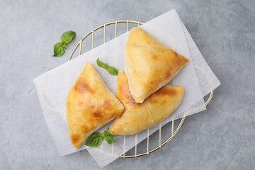 Delicious samosas and basil on grey table, top view