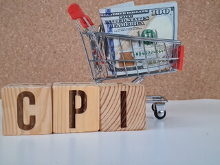 Dollars in a shopping cart and wooden blocks with word cpi