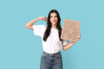 Young woman holding cardboard with text GRL PWR on blue background. Feminism concept