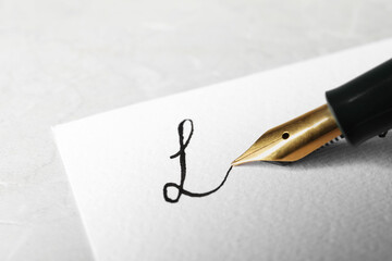 Signing on sheet of paper with fountain pen at gray table, closeup. Space for text