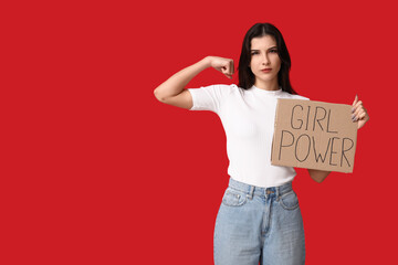 Young woman with sign GIRL POWER flexing muscles on red background. Feminism concept