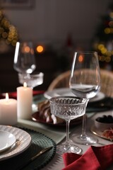 Christmas table setting with burning candles, appetizers and dishware indoors, closeup