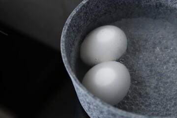 Chicken eggs boiling in saucepan on electric stove, closeup