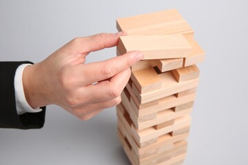 Woman playing Jenga on light gray background, closeup