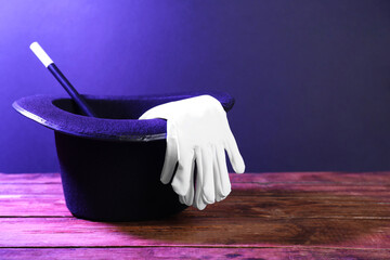 Top hat, gloves and wand on wooden table, space for text. Magician equipment