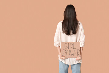 Young woman with sign GIRL POWER on beige background, back view. Feminism concept