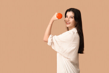 Young woman with dumbbell on beige background. Feminism concept