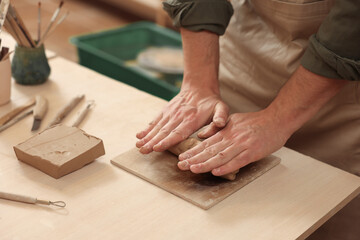 Fototapeta na wymiar Man crafting with clay at table indoors, closeup