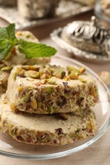 Tasty halva with pistachios and mint on table, closeup