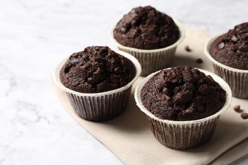 Tasty chocolate muffins on white marble table, space for text