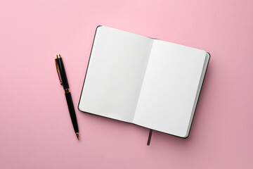 Open notebook with blank pages and pen on light pink background, top view. Space for text - obrazy, fototapety, plakaty
