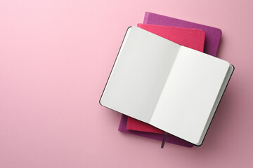 Different notebooks on light pink background, top view. Space for text