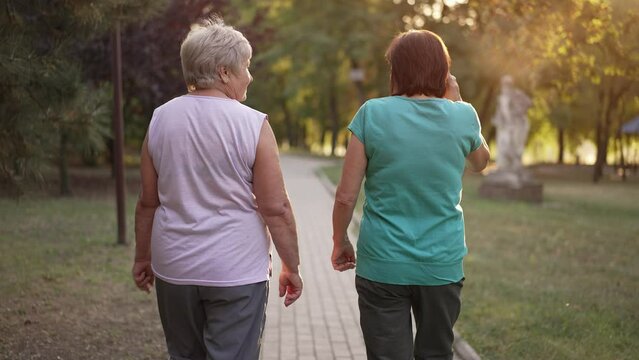 Back view of two women walking in the park