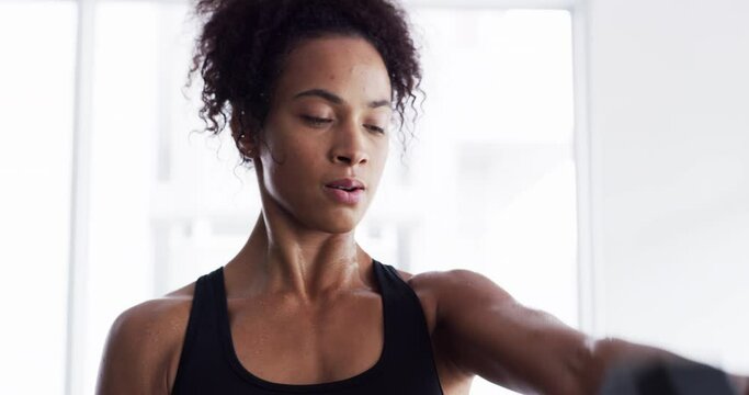 Woman, dumbbell and exercise for fitness in gym, health and wellness in training for strong core. Female person, equipment and weight lifting for muscle development, commitment and breathe in cardio