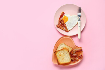 Plates with tasty bacon, heart made of fried egg and toasts on pink background - obrazy, fototapety, plakaty